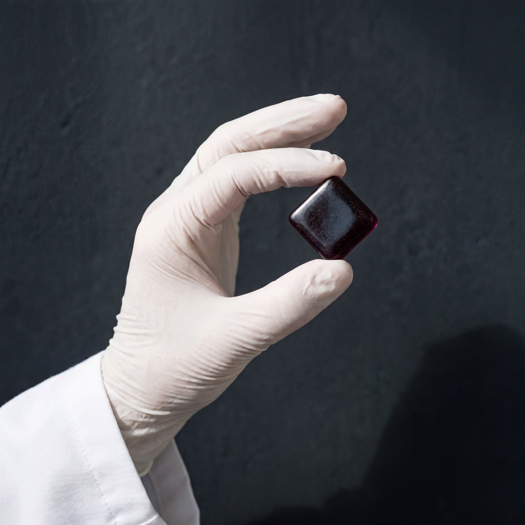 A gloved hand holding a single TW-01 gummy