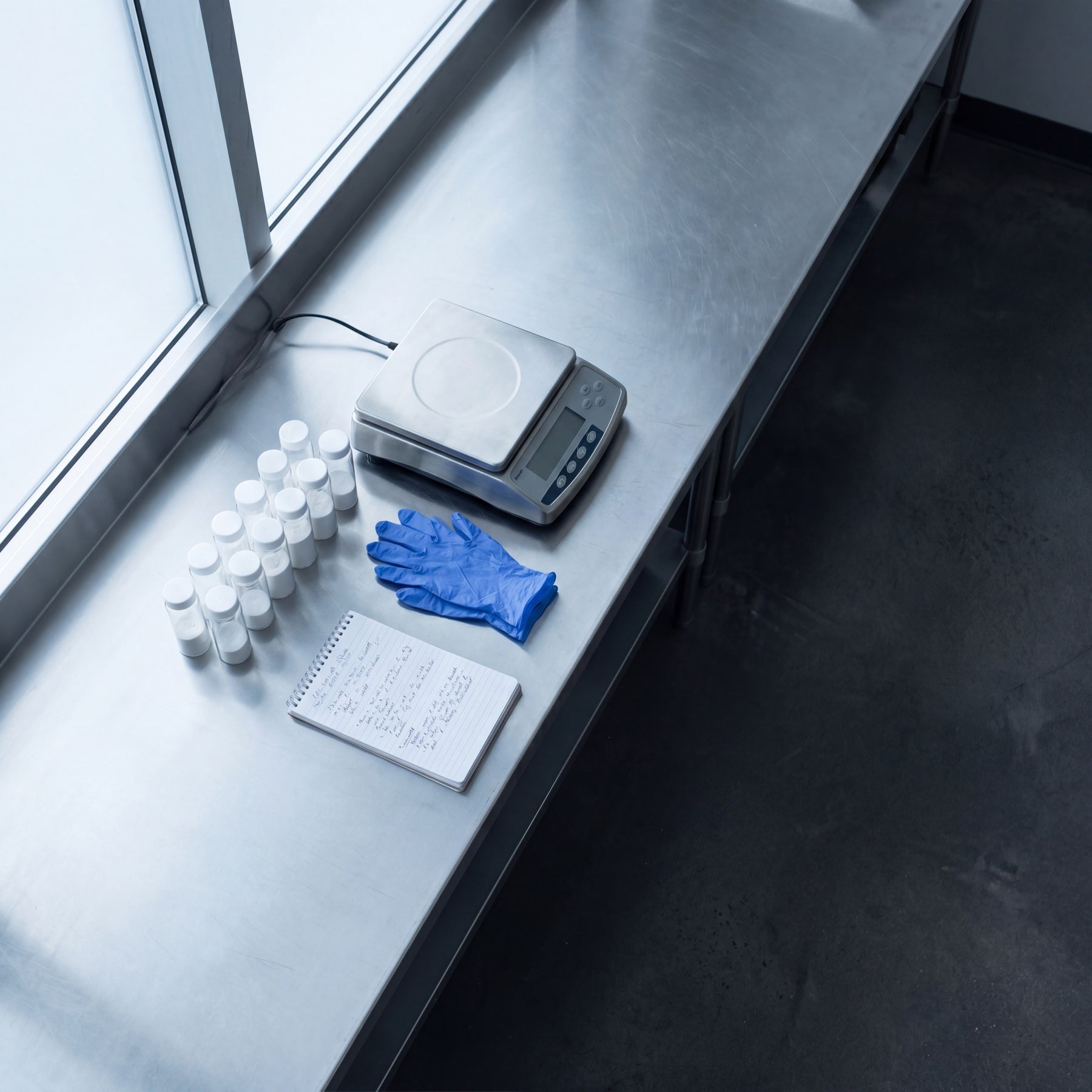 A lab counter with a scale, sample vials, and a formulator's notebook