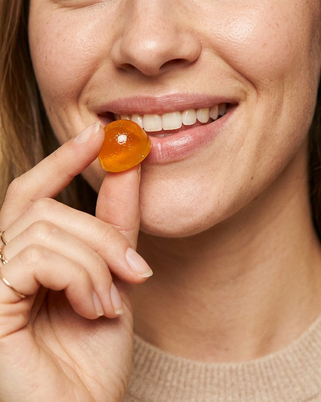 Someone smiling while holding a TW-02 citrus gummy