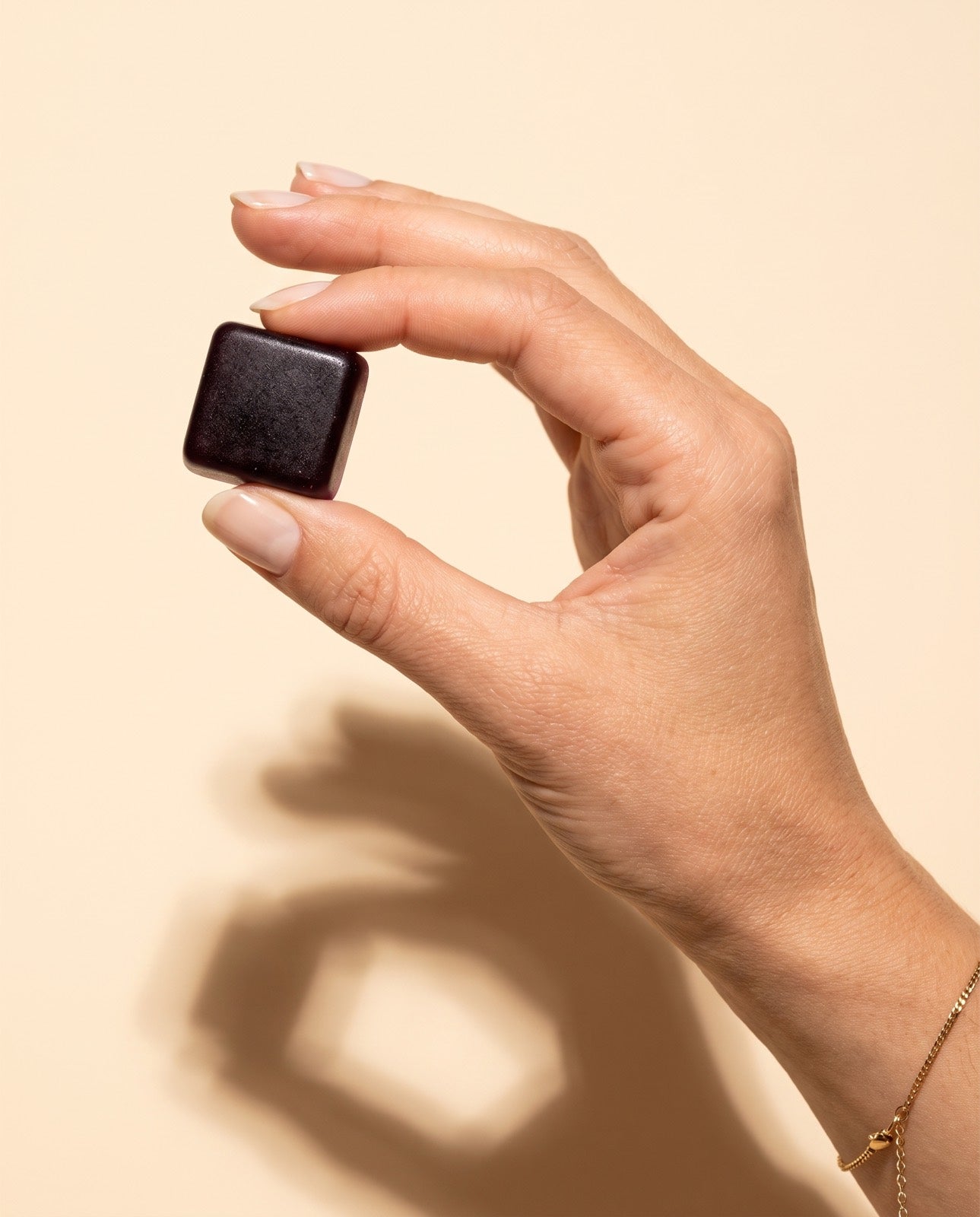 A TW-01 gummy held up between two fingers